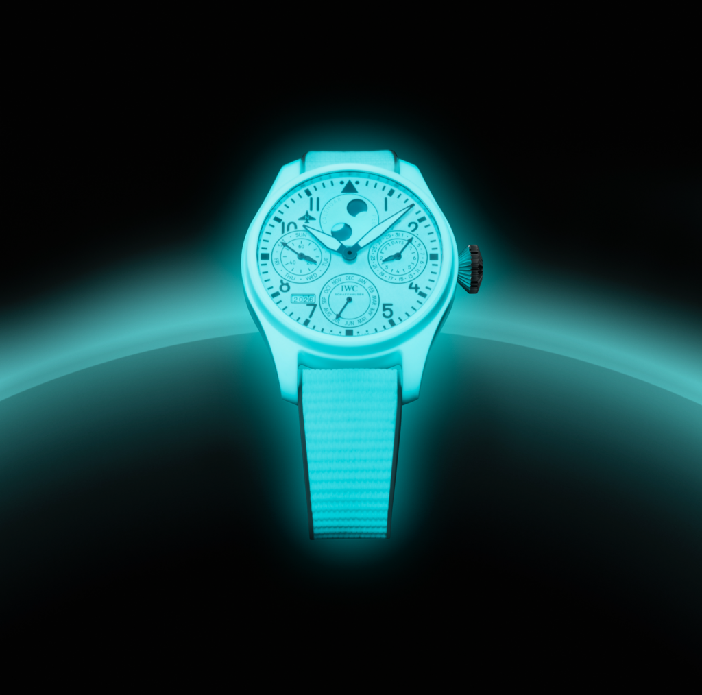 IWC CERALUME 1 - Petróleo y Energía Luminous cyan IWC wristwatch with white dial and multiple subdials, glowing against a dark background.