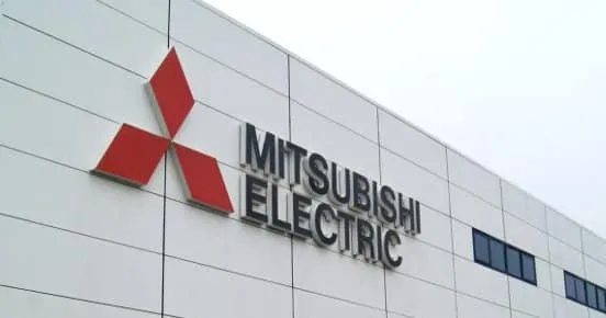 Mitsubishi Electric logo (red three-diamond mark) on the side of a white modern building exterior with the text 'MITSUBISHI ELECTRIC'.
