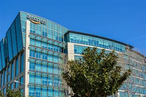 Modern glass office building with a clear blue sky and a tree in the foreground.