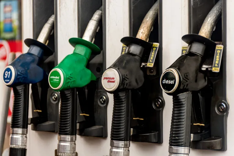 Row of fuel nozzles at a gas pump: blue 91 octane, green unleaded, and black diesel handles.