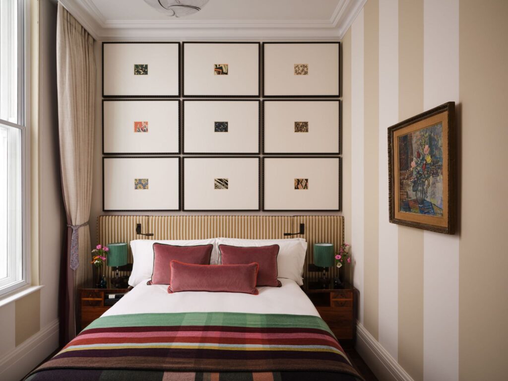 RF44D8~1 - Petróleo y Energía Bedroom with a grid of white-framed panels above a striped upholstered headboard and a multicolor striped duvet on the bed.