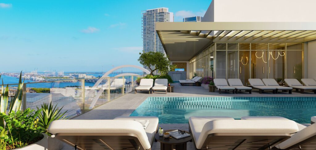 ROC3 - Petróleo y Energía Rooftop pool area with white lounge chairs, glass railing, greenery, and a city harbor view.
