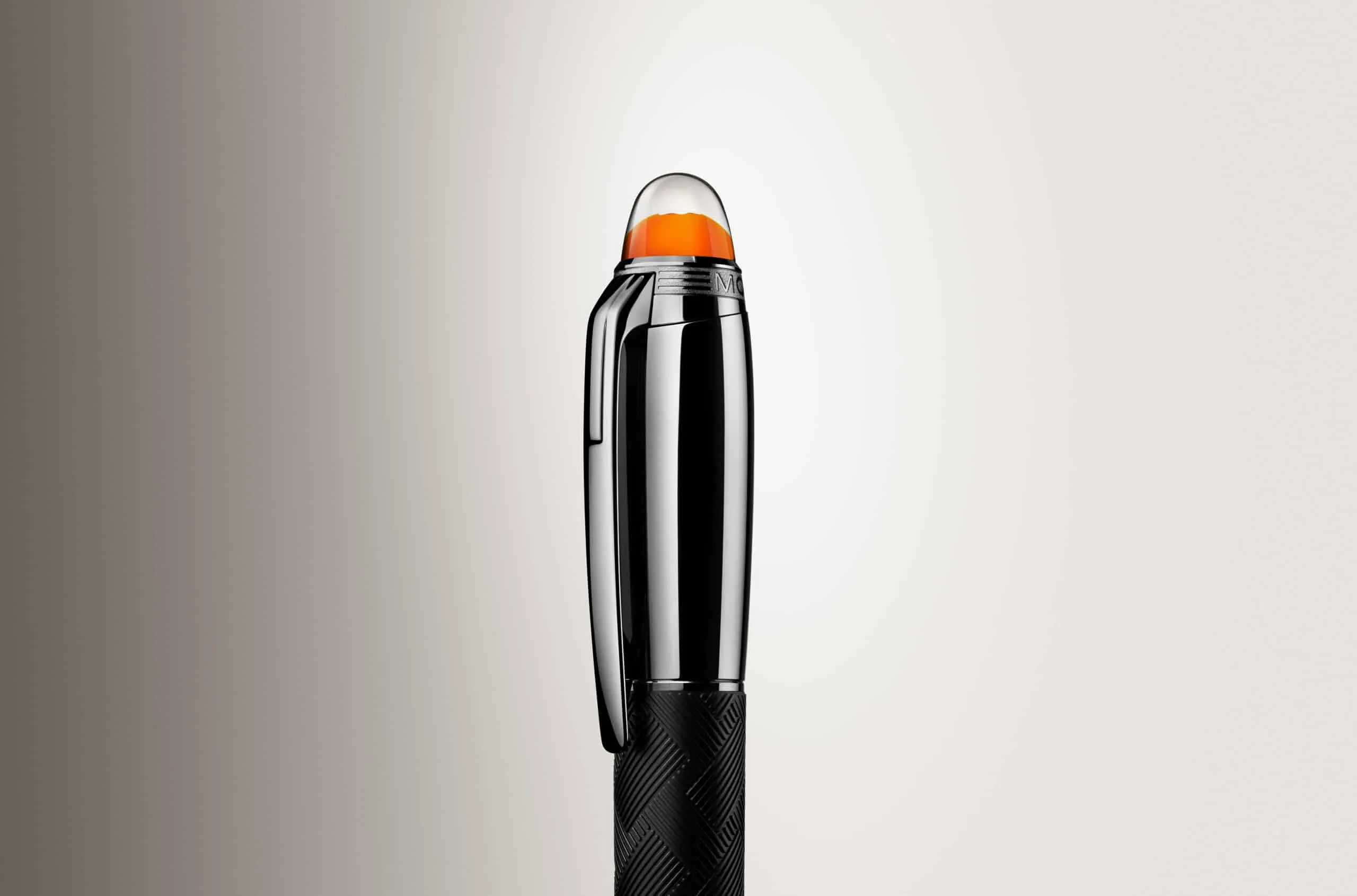 Close-up of a chrome lighter with an orange translucent cap and textured black grip, standing upright against a beige gradient.
