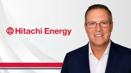 Hitachi Energy logo on the left with a smiling man in a navy suit on a light gray background.
