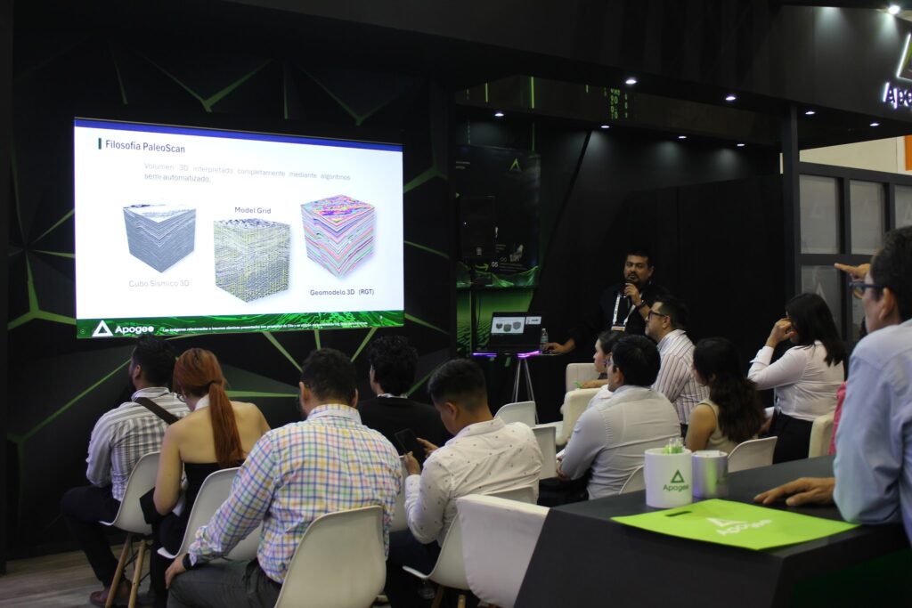 image - Petróleo y Energía Conference room presentation: a speaker with microphone beside a large slide showing 'Filosofia PaleoScan' and three 3D cube diagrams. Audience seated and watching.