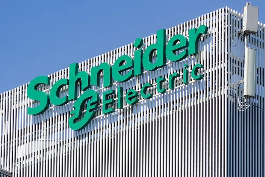 Schneider Electric logo on a modern building facade with green lettering against a blue sky.