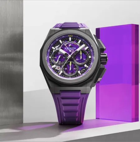 Skeleton-dial Zenith El Primero chronograph watch with purple accents and purple strap between metallic panels.