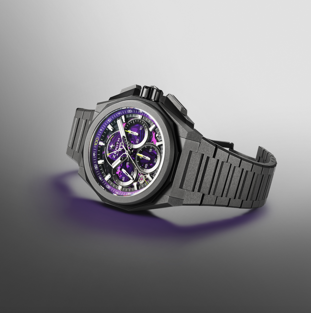 zenith_ultraviolet 4 - Petróleo y Energía Skeleton-style wristwatch with purple accents and a gray metal bracelet on a gradient gray background.