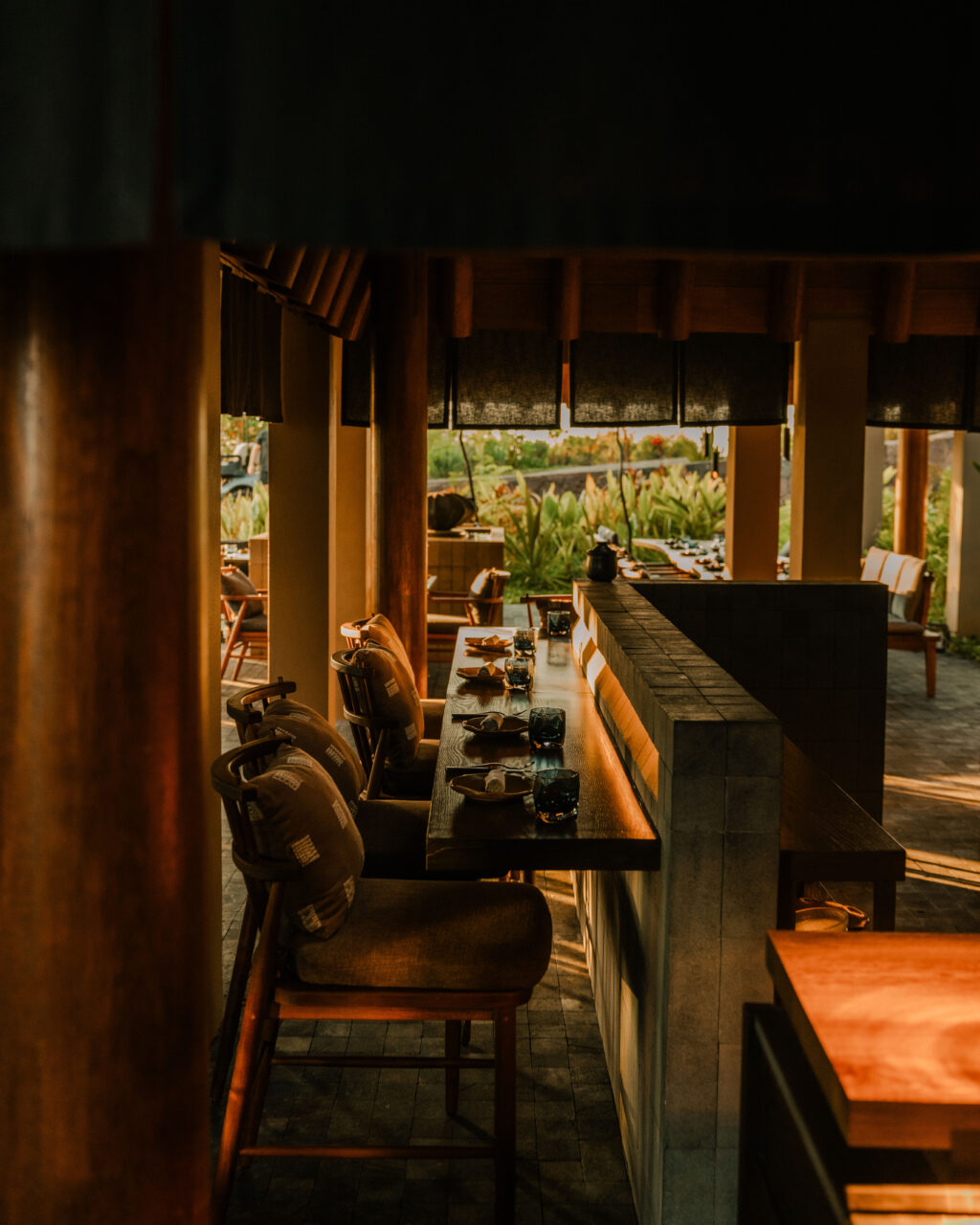 0I5A3064 - Petróleo y Energía Dimly lit restaurant interior with a long wooden bar/table set for dining and chairs along one side