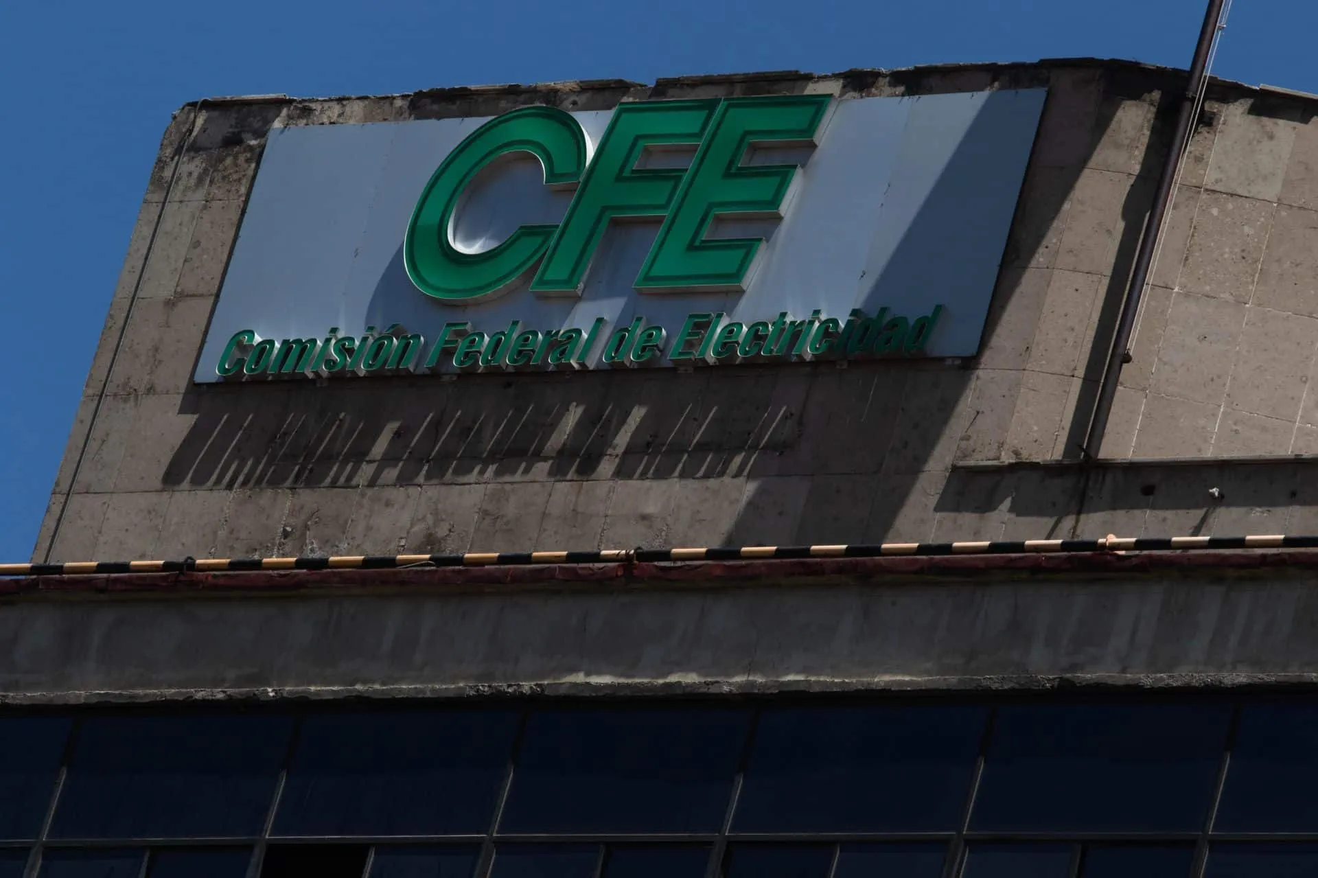 CFE sign on a concrete building with blue sky, reading 'Comisión Federal de Electricidad'