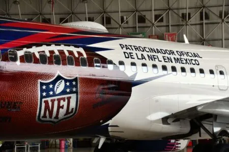 Plane fuselage in a hangar with bold 'Patrocinador oficial de la NFL en México' text and NFL logo on the red livery.