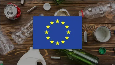 Blue card with the European Union flag (circle of yellow stars) placed on a wooden table surrounded by plastic bottles and trash, highlighting pollution cues.