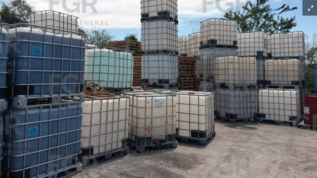 Stacked plastic IBC totes on pallets in an outdoor storage yard.