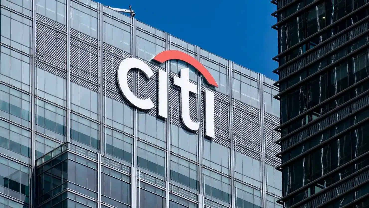 Citi logo on a glass office building with a red curved arc above the letters,” indicating a corporate branding scene.