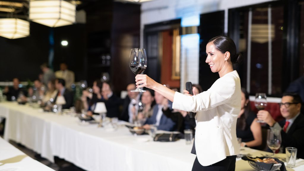 FLA_2592 - Petróleo y Energía Woman in a white blazer toasting with a wine glass at a formal dinner event.