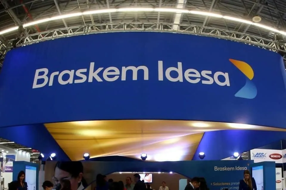 Booth with Braskem Idesa logo on a blue curved wall at a trade show hall.