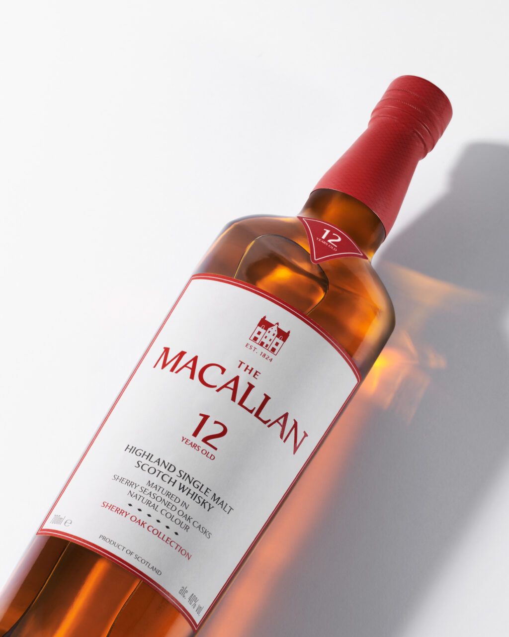 MAC-2025-Sherry-Oak-12YO-Mood-Shot-Primary-Website-Card-4x5-RGB-150dpi - Petróleo y Energía Bottle of The Macallan 12 Years Old Highland Single Malt Scotch Whisky, tilted with red cap and label visible.