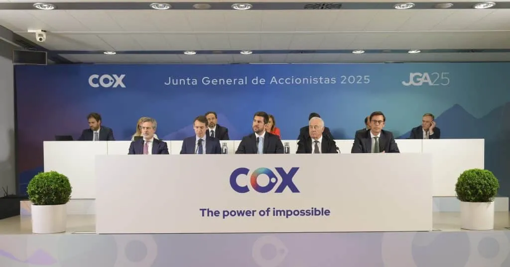 Panel of executives at a COX shareholders' meeting, seated behind a white desk with the COX logo and slogan 'The power of impossible'. The backdrop reads 'Junta General de Accionistas 2025'.