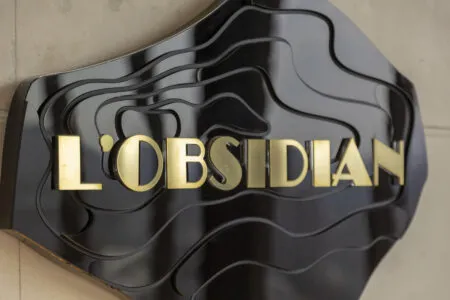 Close-up of a glossy black sign with wavy black accents and large gold letters partly visible.