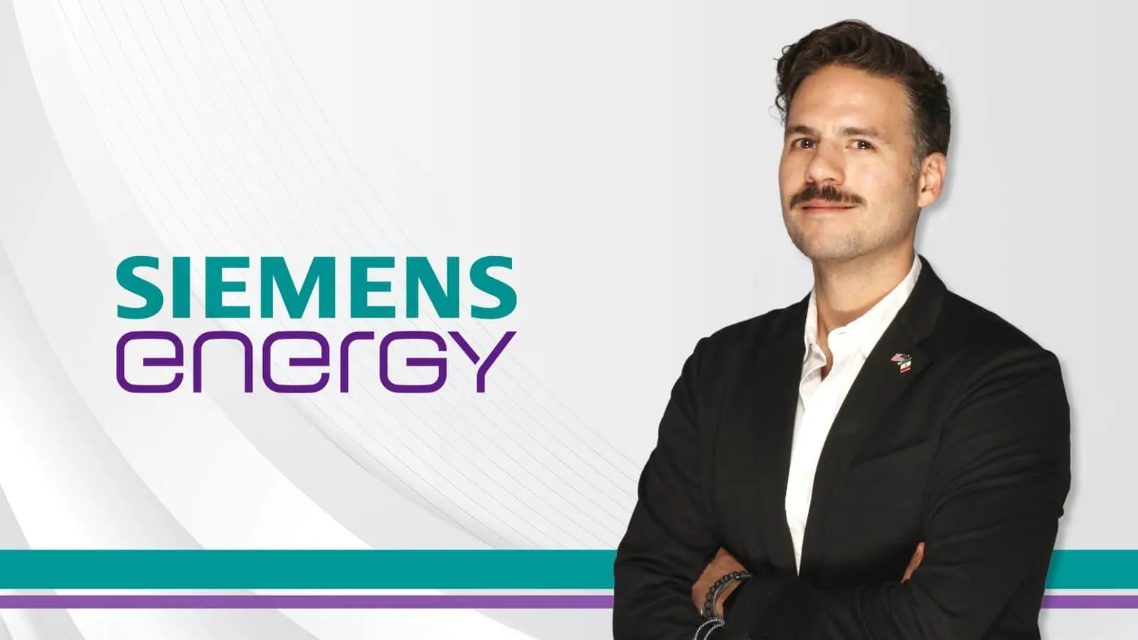 Professional man in a suit with arms crossed beside a Siemens Energy banner on a gray backdrop.