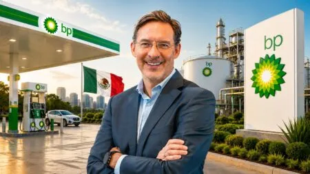 Businessman in a suit with arms crossed at a BP gas station, Mexico flag in the background and industrial refinery structures nearby