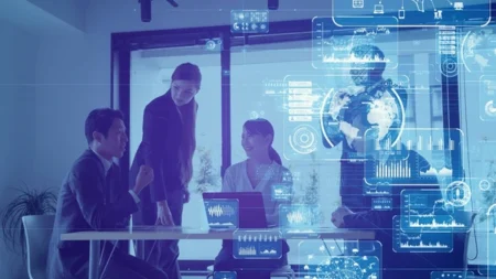 Group of professionals in a meeting surrounded by holographic charts and data projections, in a blue-toned conference room.