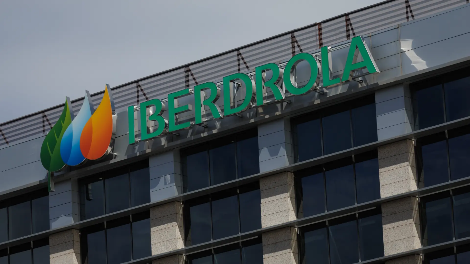 Corporate office building exterior with a green 'IBERDROLA' sign and multicolored leaf logo on the façade