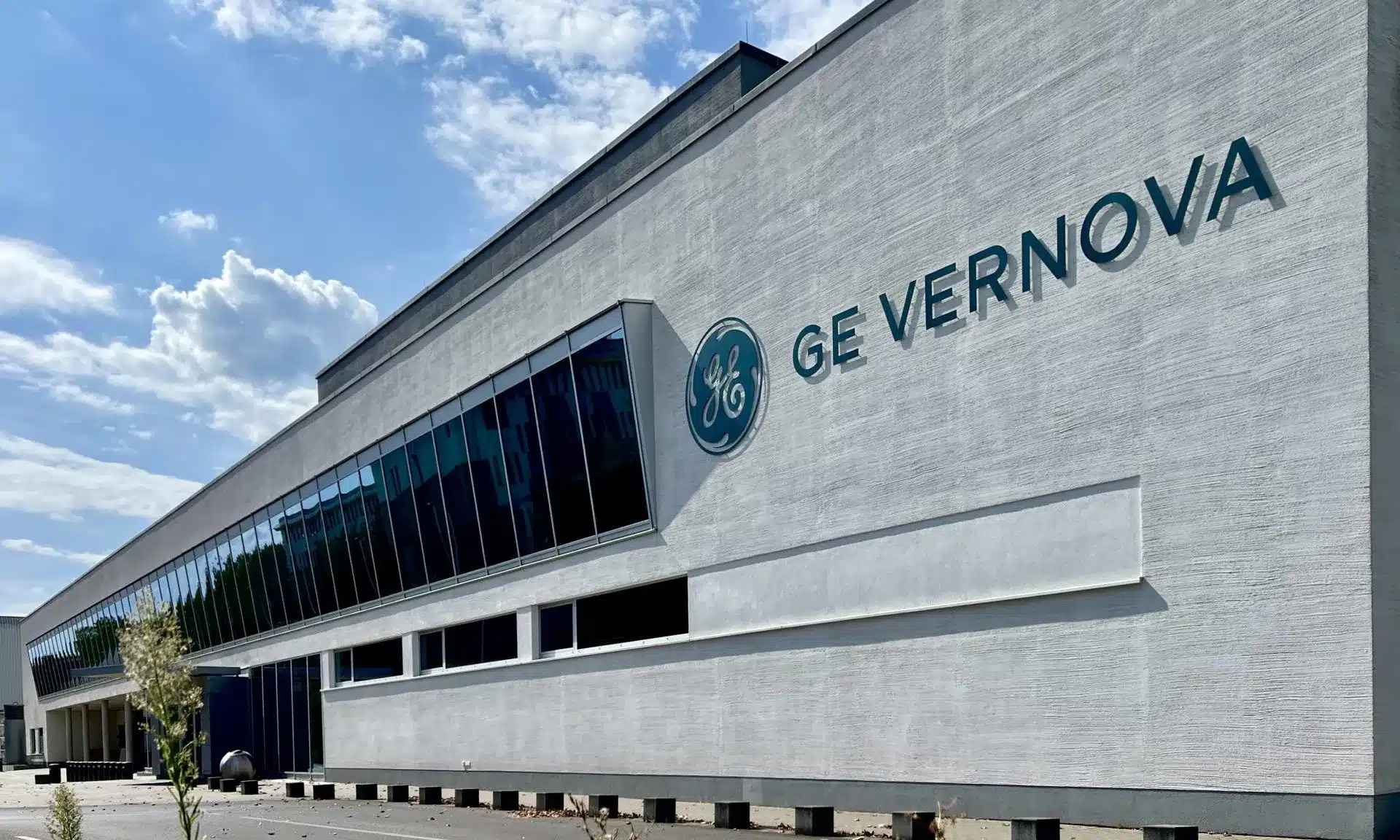 GE Vernova corporate building with the GE logo on a textured white wall against a blue sky.