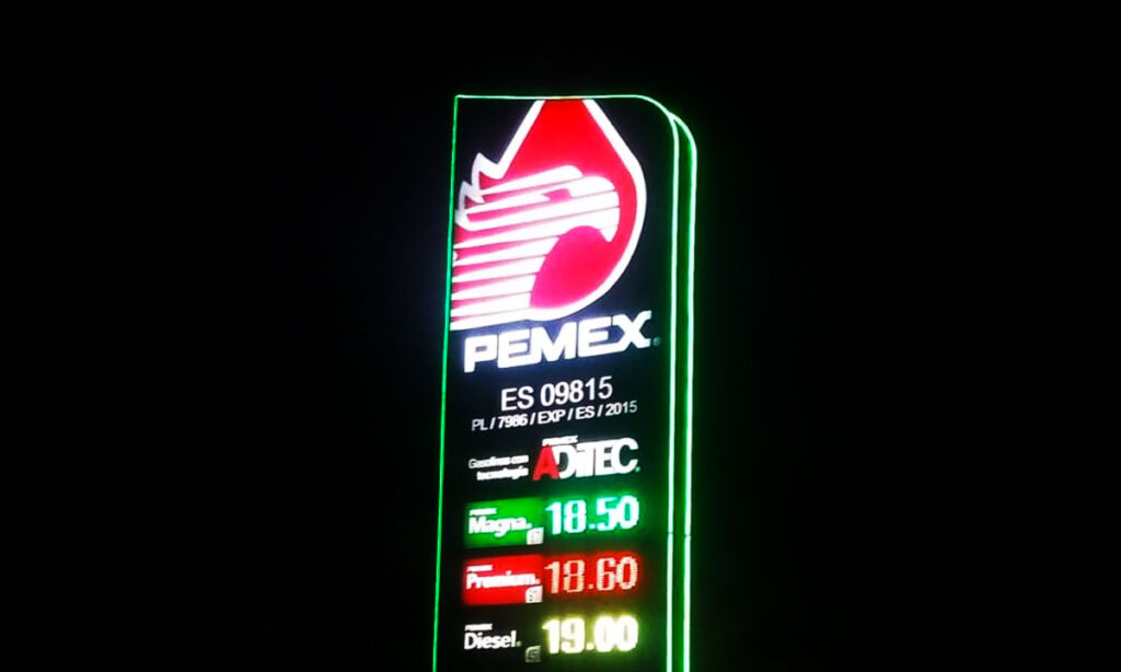 Neon PEMEX sign at night showing fuel prices: Magna 18.50, Premium 18.60, Diesel 19.00, with large red logo above.