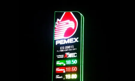 Neon PEMEX sign at night showing fuel prices: Magna 18.50, Premium 18.60, Diesel 19.00, with large red logo above.
