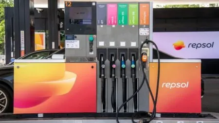 Fuel pump at a Repsol station with multiple hoses and a digital display panel above, showing different fuel options on colored tabs.