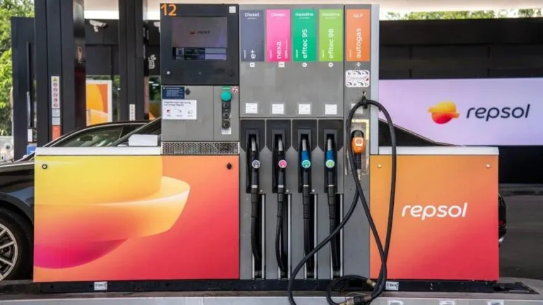 Fuel pump at a Repsol station with multiple hoses and a digital display panel above, showing different fuel options on colored tabs.