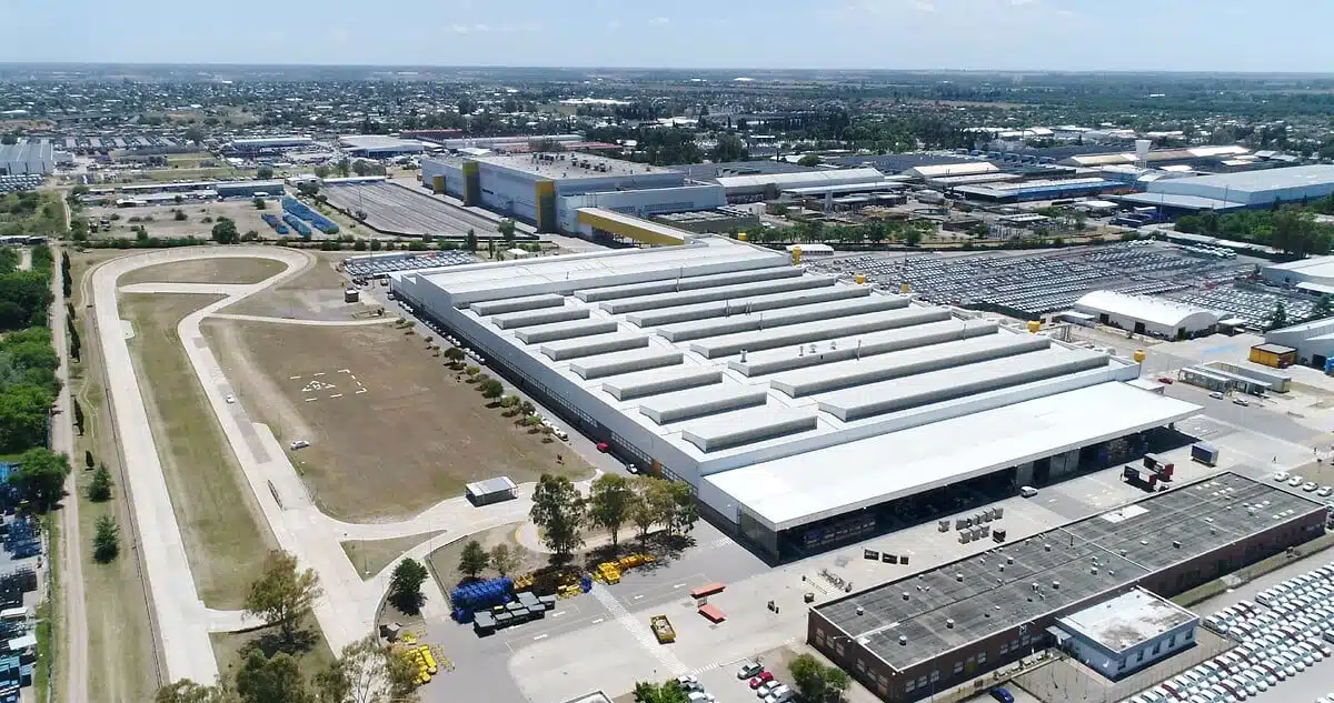 Aerial view of a large industrial complex with long white-roof warehouses, loading bays, and surrounding parking areas.