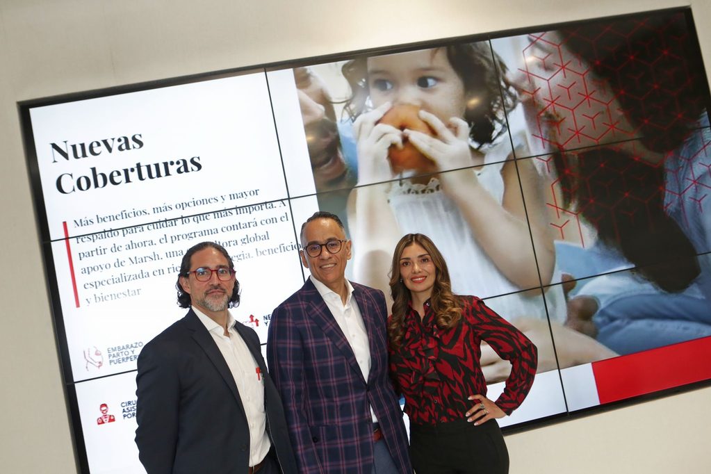 1790346730831 - Petróleo y Energía Three professionals pose in front of a large screen displaying 'Nuevas Coberturas' and a child eating an orange.