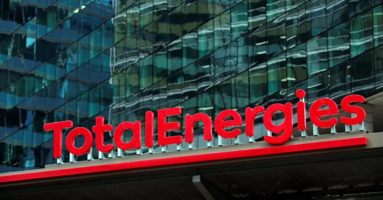 TotalEnergies logo in bright red letters on a glass-fronted building façade.