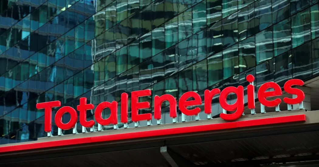 TotalEnergies logo in bright red letters on a glass-fronted building façade.