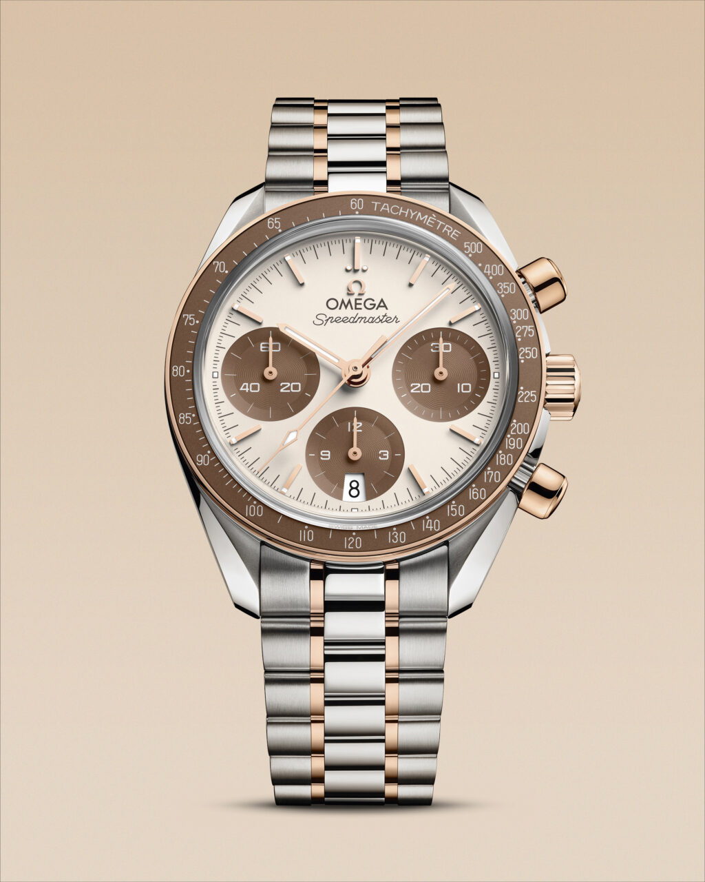Stacked from 21 images Method=B R=8S=4 - Petróleo y Energía Close-up of an Omega Speedmaster two-tone chronograph with a rose-gold and steel bracelet on a beige background, showing the dial and tachymeter bezel.