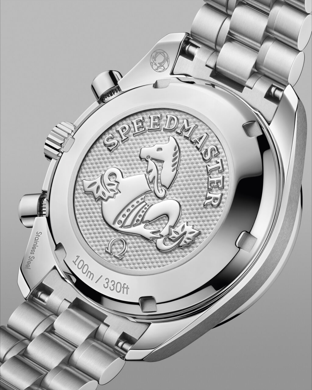 Stacked from 17 images Method=B R=8S=4 - Petróleo y Energía Close-up of a stainless steel Speedmaster watch case back with the seahorse emblem and'Speedmaster' engraving, showing 100m/330ft water resistance.