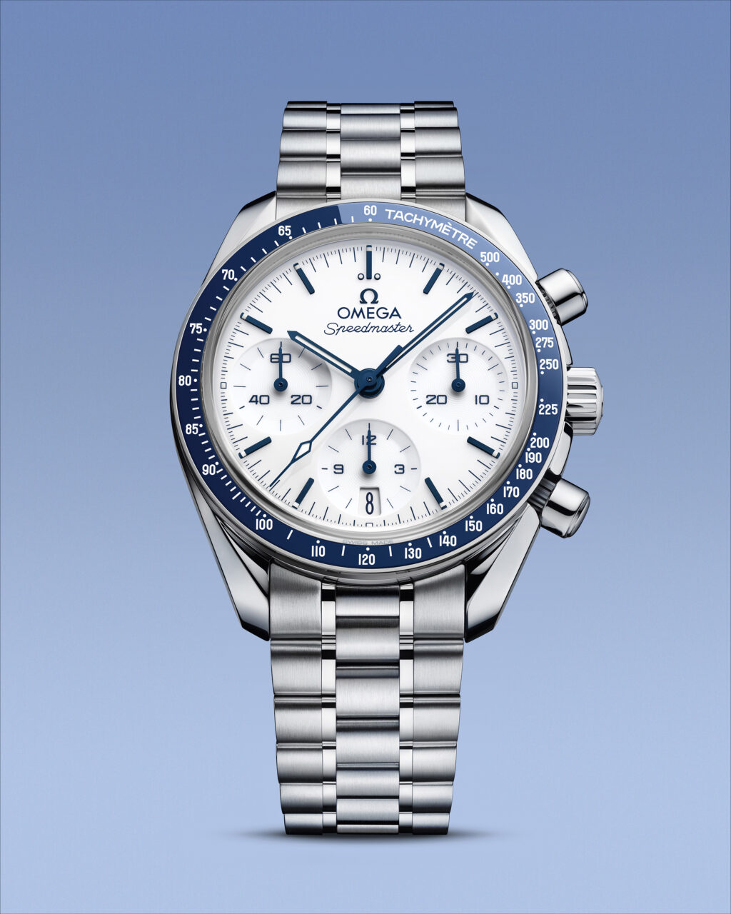 Stacked from 21 images Method=B R=8S=4 - Petróleo y Energía Close-up of an Omega Speedmaster chronograph with a blue tachymeter bezel and stainless steel bracelet against a blue sky background.