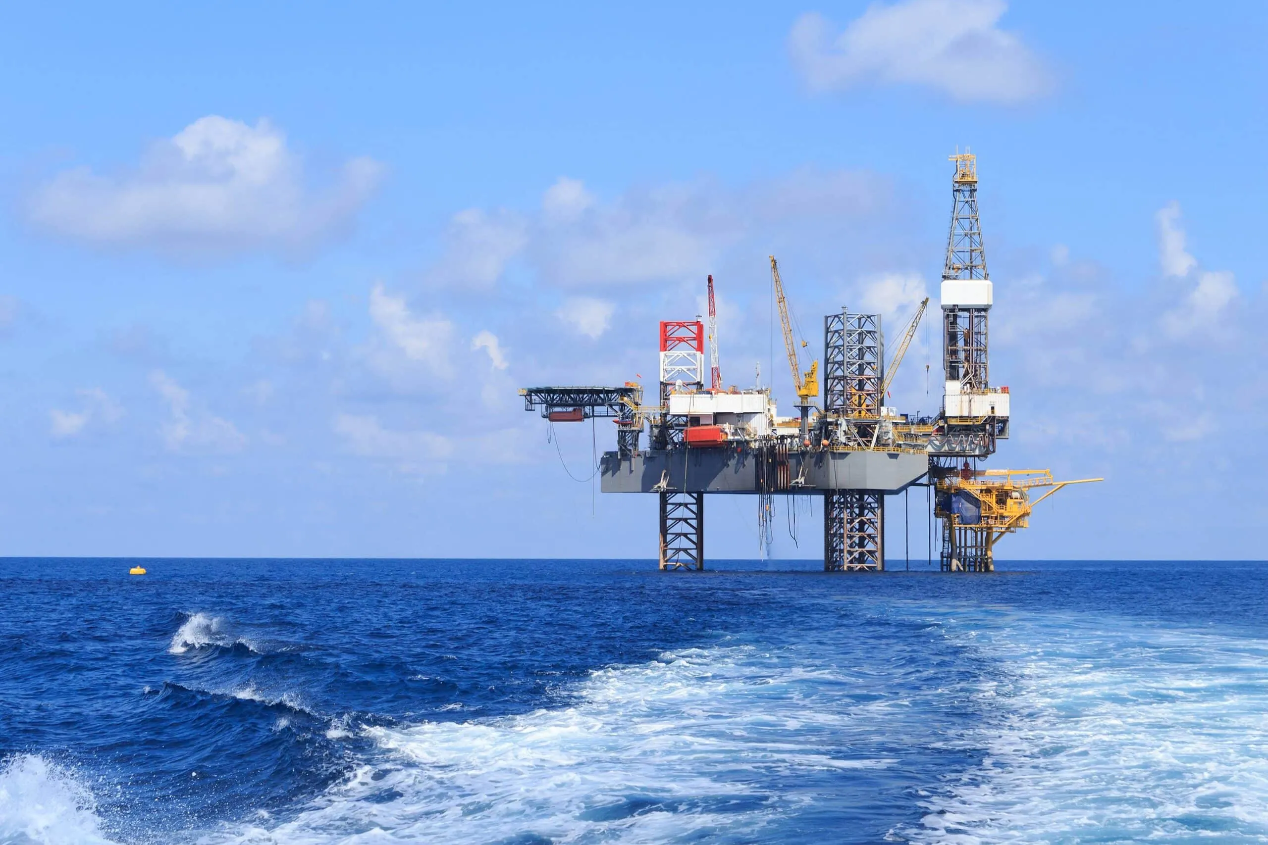 Offshore oil rig rising from the blue ocean under a clear sky.