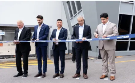 Five men in suits cutting a blue ribbon at a ceremonial outdoor opening event.