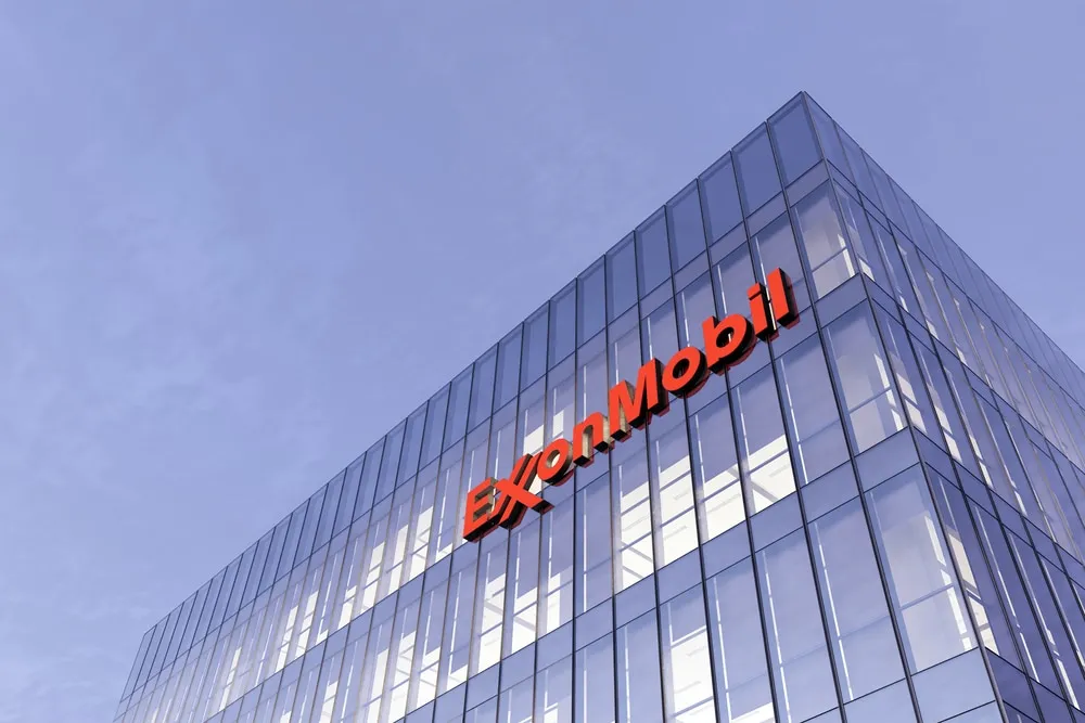 ExxonMobil sign on a glass office building against a blue sky.
