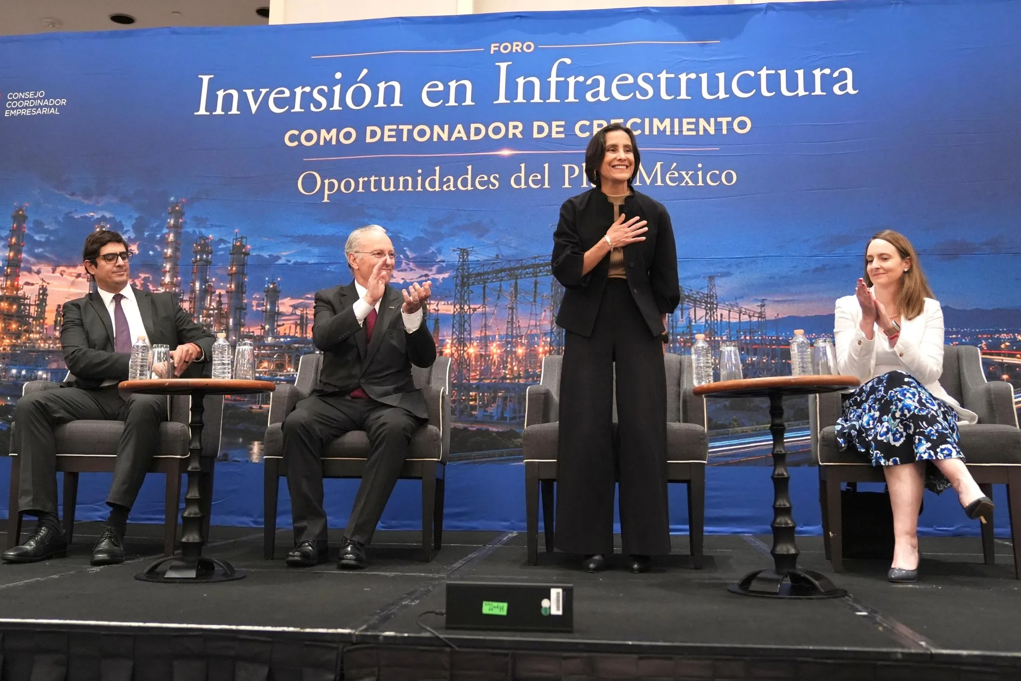 Panel discussion on infrastructure investment with four speakers on a stage and a blue backdrop behind them (text reads 'Inversión en Infraestructura').