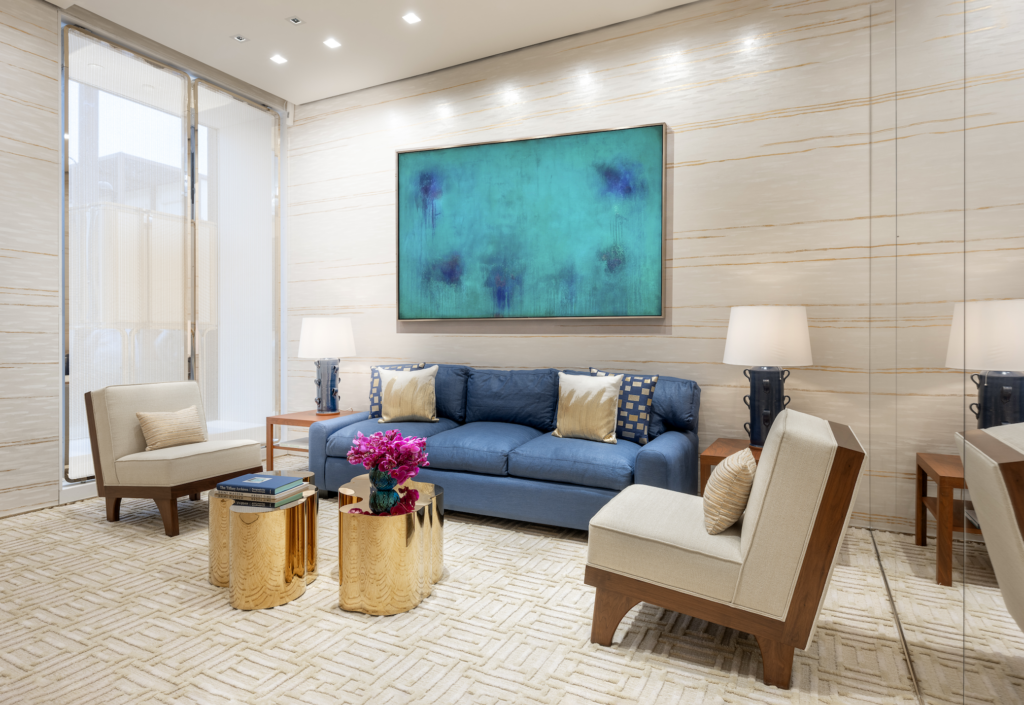 NUEV BOUTIQUE TIFFANY 2026-09-24 a las 44342 pm - Petróleo y Energía Modern living room with a blue sofa, beige chairs, and a teal abstract painting on a striped light wall.