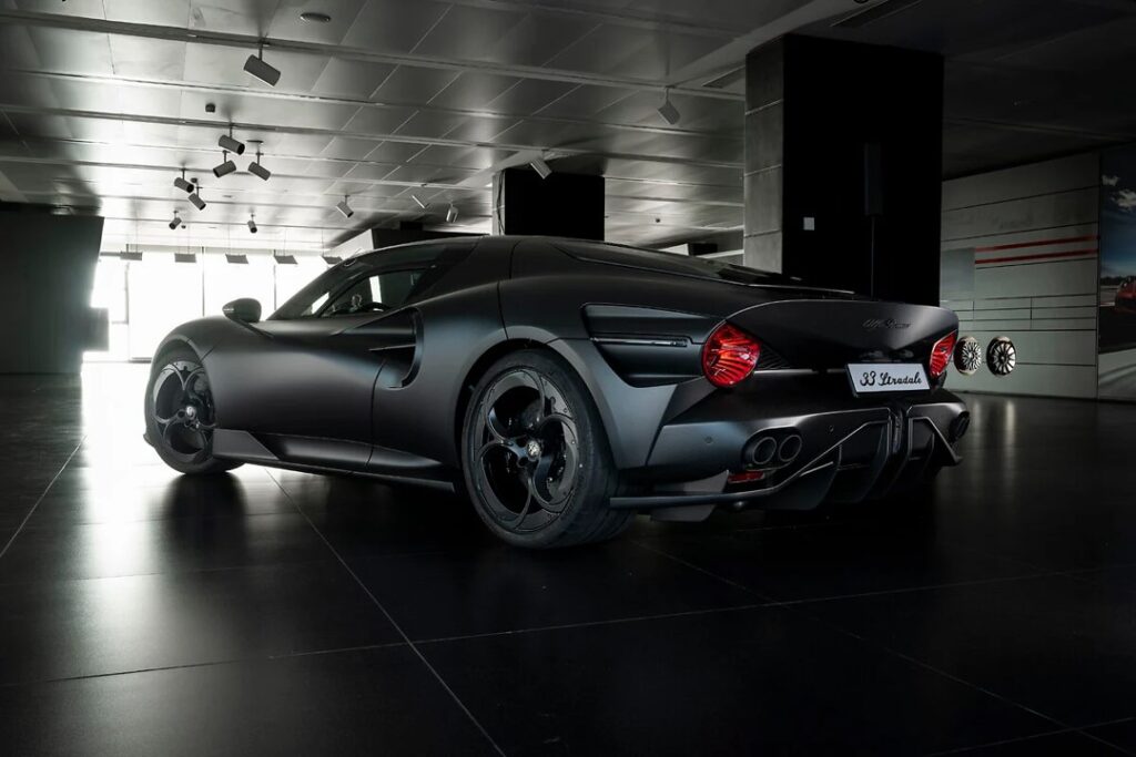 Picture4 - Petróleo y Energía Rear three-quarter view of a matte black luxury sports car in a showroom with overhead spotlights.