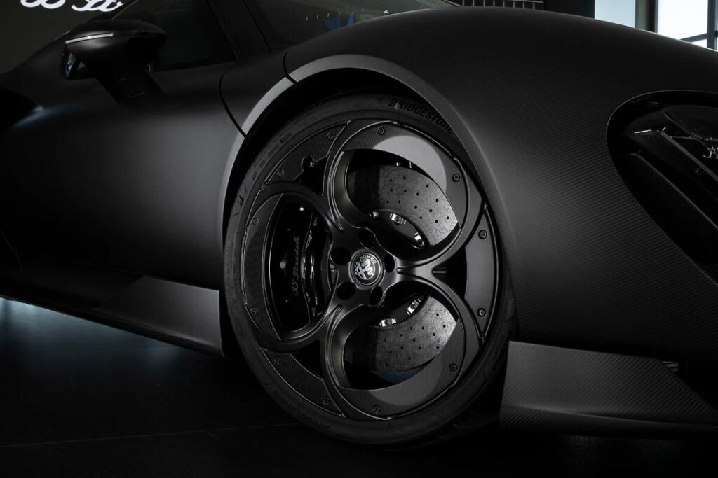 Picture7 - Petróleo y Energía Close-up of a black alloy wheel with drilled brake rotors on a matte car body