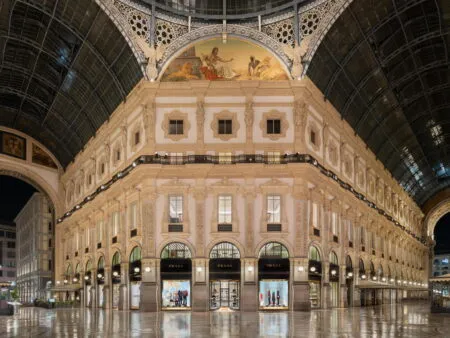 Interior of a grand historic shopping arcade with ornate arches and a Prada storefront on the ground level in the center of the image.