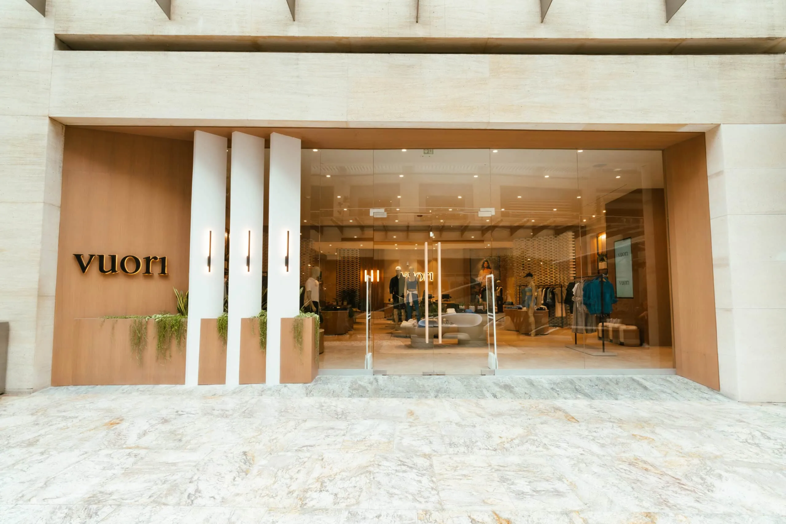 Vuori storefront with glass doors and warm interior lighting, beige stone exterior.