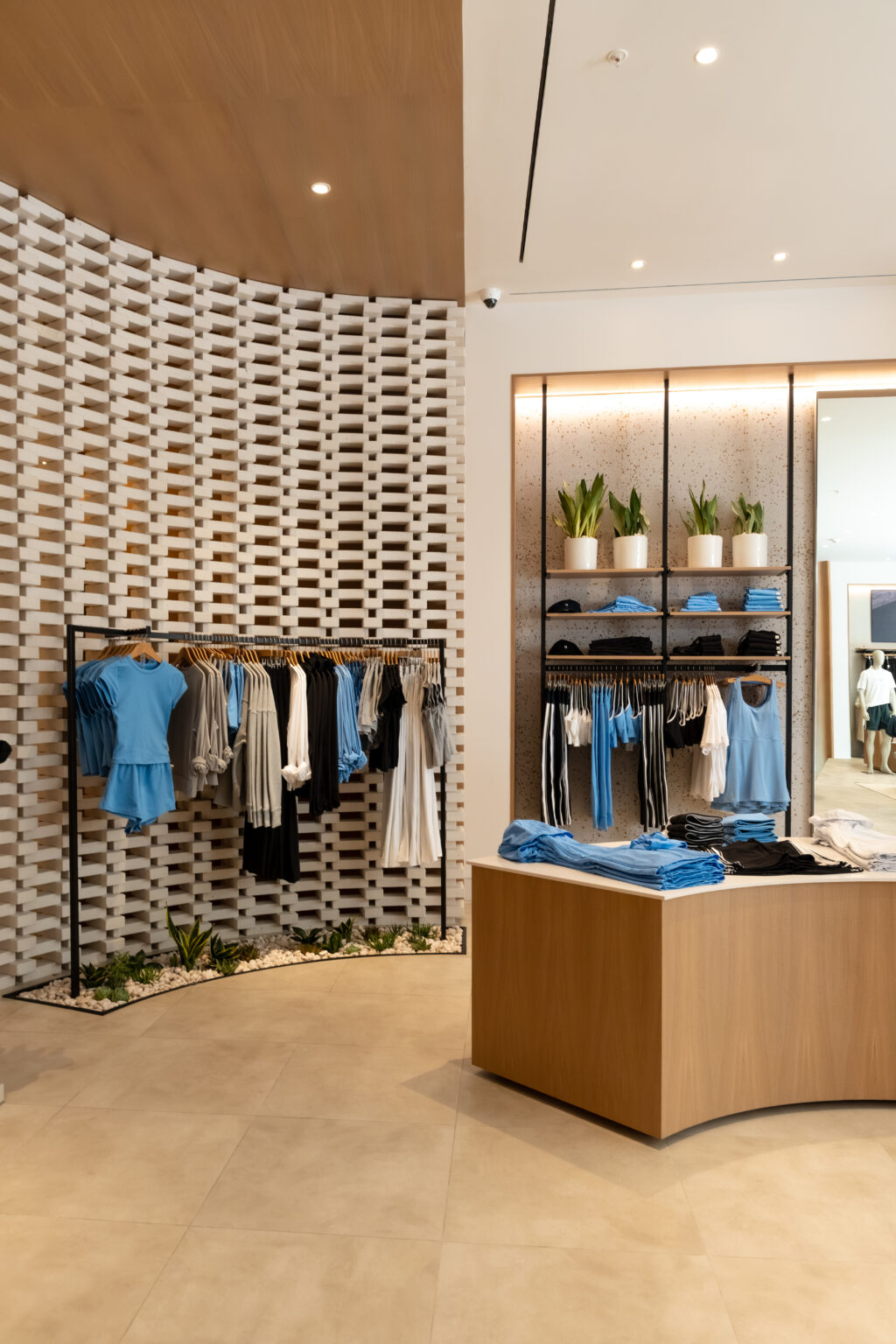 VUORI-D2-STORE-13 - Petróleo y Energía Boutique clothing store interior with blue garments on racks and a wooden display table of folded blue shirts.