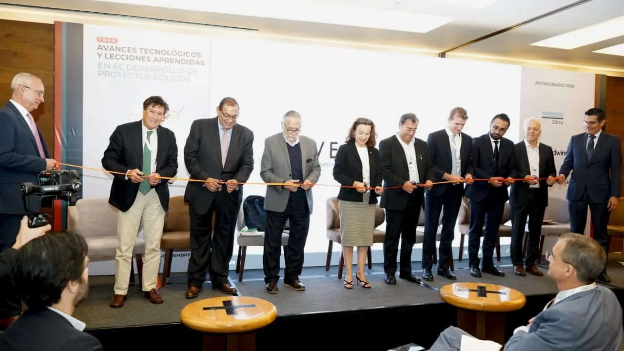 Ten professionals cut a ribbon during a formal ceremony on a stage.